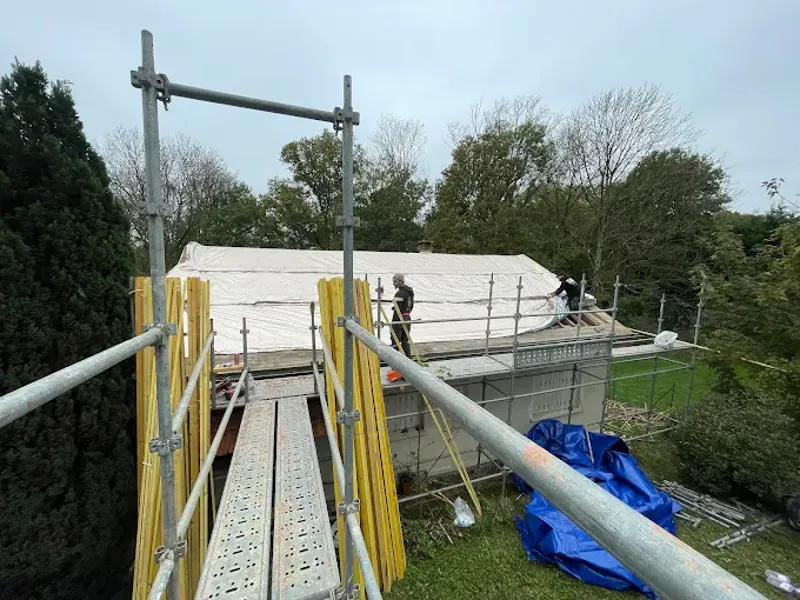 Toiture couverte d'une bâche de protection, couvreurs sur l'échafaudage