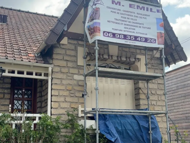 Échafaudage installé devant un pignon de maison avec bâche de protection