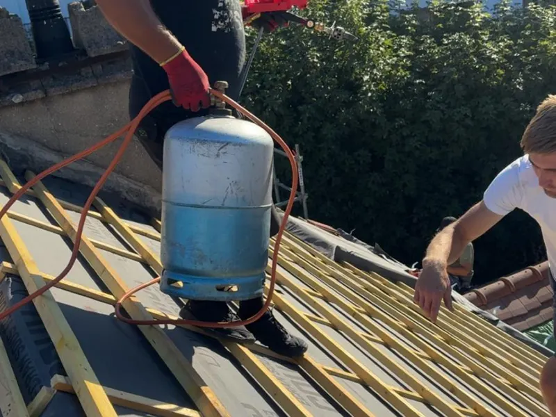 Couvreur sur une toiture en cours de réfection, liteaux posés sur écran sous toiture