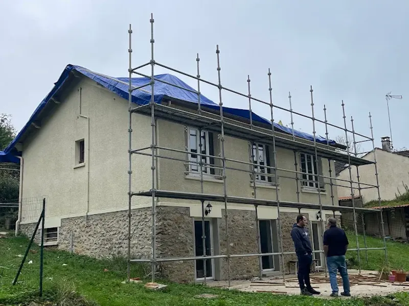 Maison avec toiture protégée par une bâche bleue et échafaudage en façade